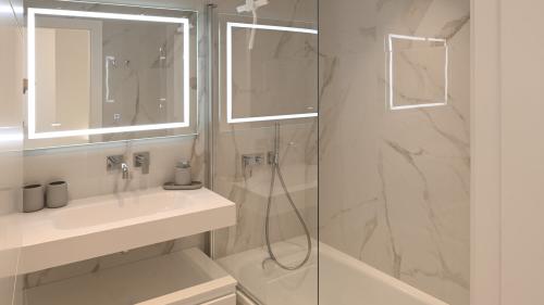 Badezimmer mit beleuchteten Spiegeln, Dusche und Badewanne