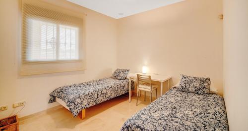 Zweibettzimmer mit geblümten Tagesdecken und kleinem Schreibtisch