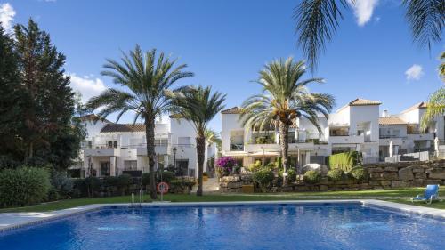 Gemeinschaftspool umgeben von Palmen und Reihenhäusern im andalusischen Stil