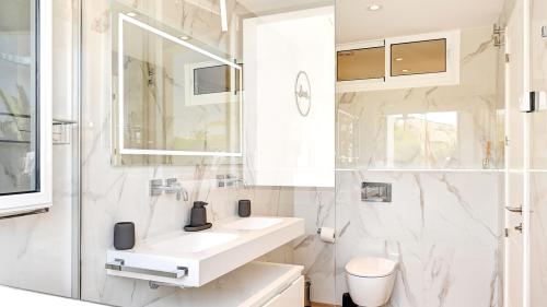 Badezimmer mit Doppelwaschbecken, begehbarer Dusche und Holzboden
