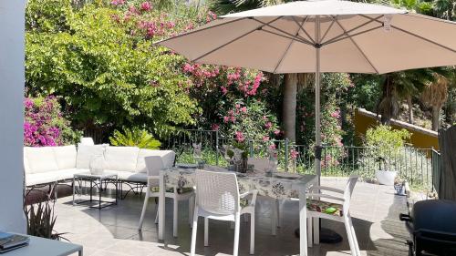 Terrassen-Essbereich mit Sonnenschirm, umgeben von Grünpflanzen