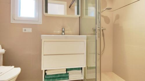 Badezimmer mit Waschtisch, Dusche und gefalteten Handtüchern