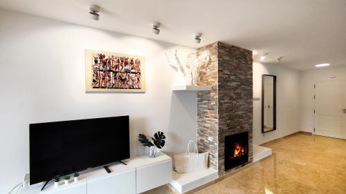Wohnbereich mit TV, Kunstwerken und steinverkleidetem Kamin