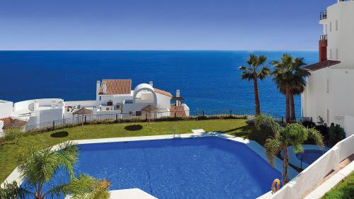 Community pool surrounded by palm trees, overlooking the sea