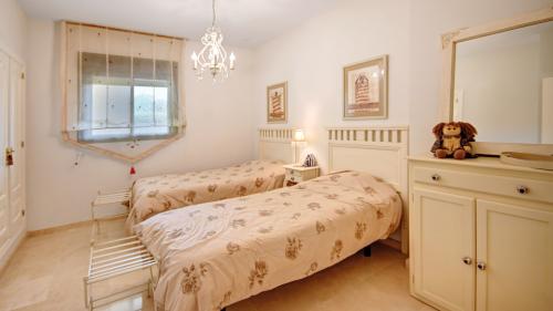 Twin bedroom with floral bedspreads and a cream dresser with mirror