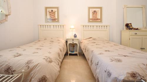 Second twin bedroom with cream headboards and dresser with mirror